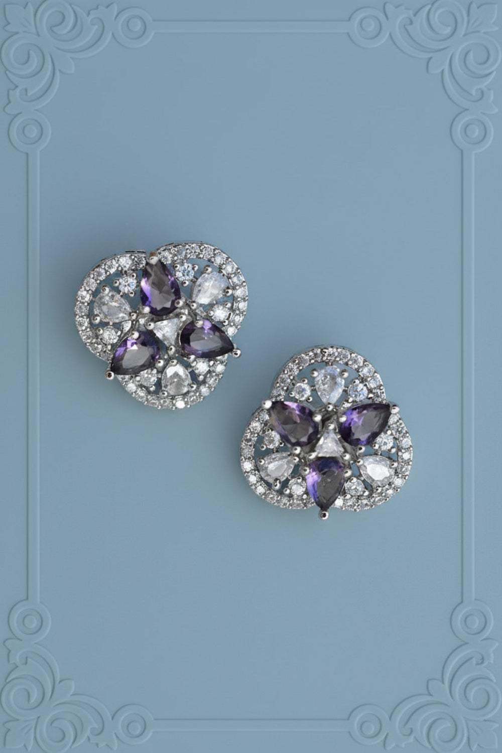 Pair of earrings with purple gemstones on a textured silver background